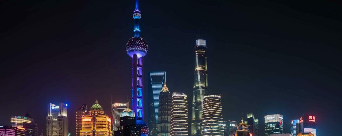 Illuminated Shanghai skyline featuring the Oriental Pearl Tower against a night sky.