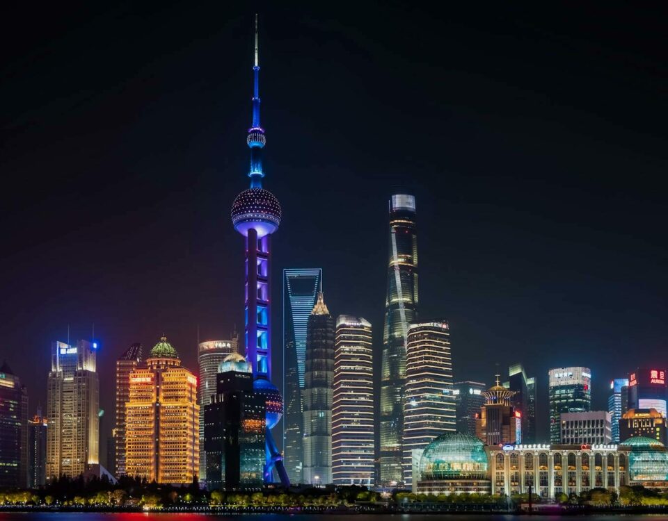 Illuminated Shanghai skyline featuring the Oriental Pearl Tower against a night sky.