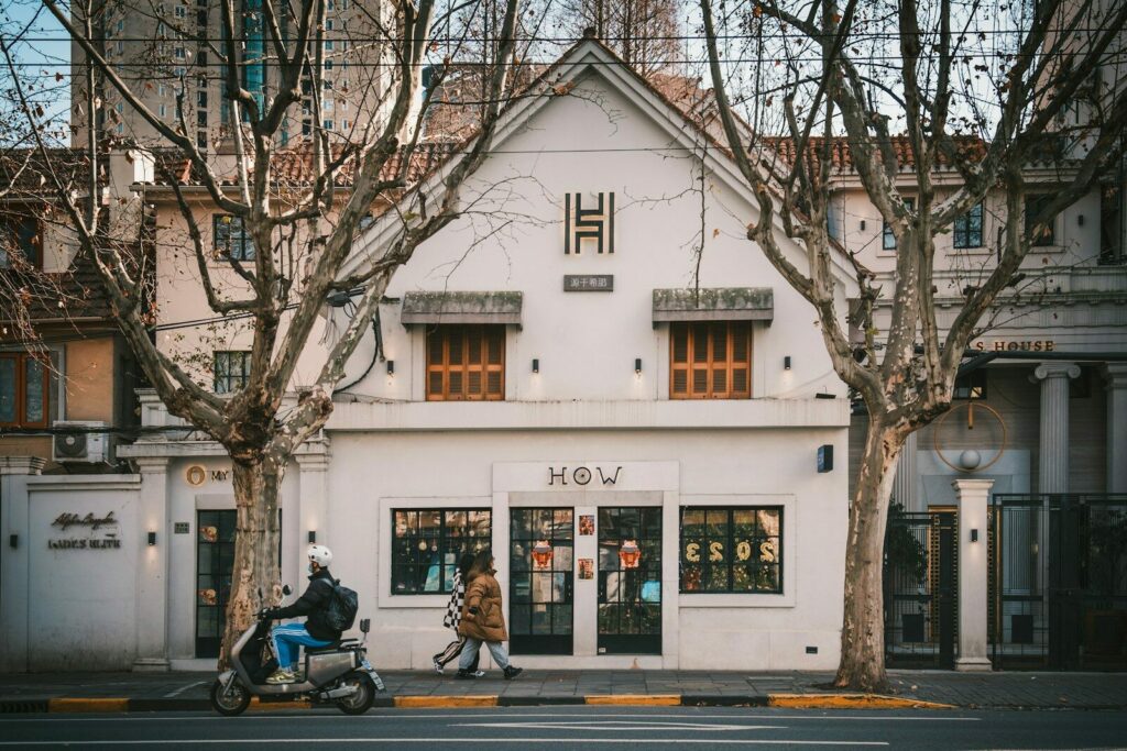 a man riding a motorcycle down a street next to a tall white building
